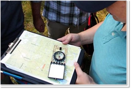 Manager using a map and compass for orientation during an outdoor training course
