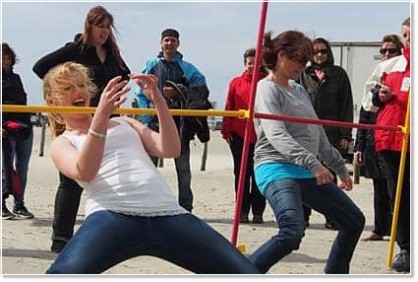 Employees doing limbo during company beach event