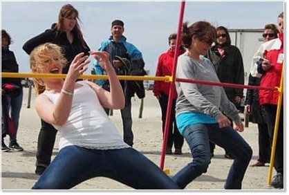 Employees doing limbo during company beach event Employees doing limbo during company beach event