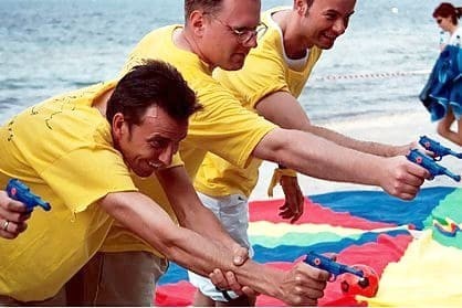 Employee team in a water pistol competition during a team event on the Baltic Sea beach