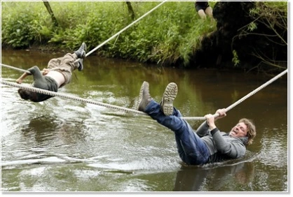 Employee crossing a stream on a rope bridge