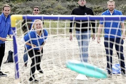 Employee throwing a frisbee during a team event on the beach in Travemünde